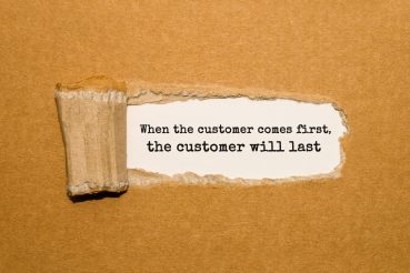 The text When the customer comes first the customer will last appearing behind torn brown paper The text When the customer comes first the customer will last appearing behind torn brown paper